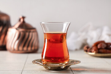 Glass of Turkish tea with pot on white tile table