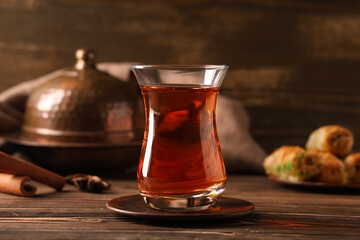Glass of Turkish tea with spices and tasty baklava on wooden background
