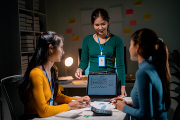 Asian businesswomen working late analyzing financial charts on a laptop in office meeting room