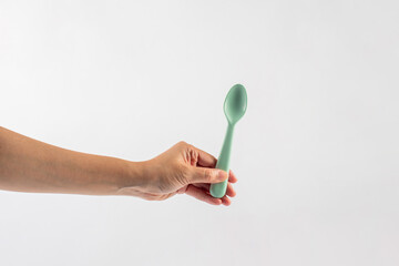 Green spoon and hand isolated on white background.