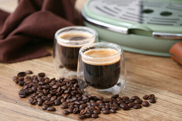 Modern coffee machine with glasses of hot espresso and beans on wooden background, closeup