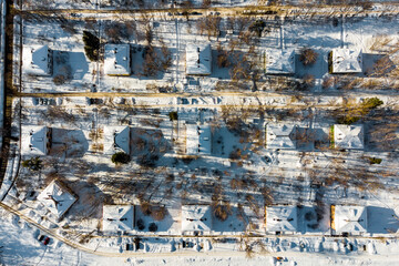 Snow-covered roofs of identical residential buildings in the suburbs, aerial view