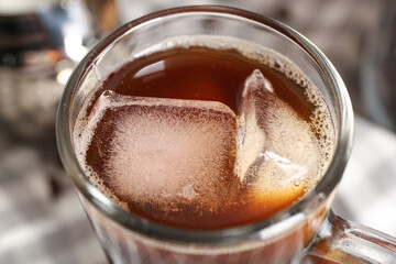 Glass cup of cold coffee with ice cubes, closeup