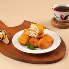 Crispy fried rolls stuffed with chicken and vegetables are served alongside a cup of coffee and a small side of pickled vegetables