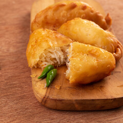 Enjoying crispy pastries bursting with rice and spices, served with fresh green chili. Perfect snack for sharing at any gathering