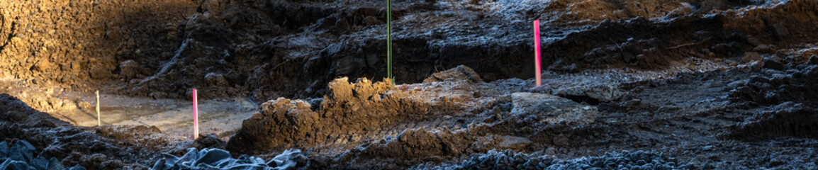 Freshly excavated residential construction job site lot, pile of fresh dirt highlighted by sun,...