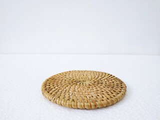 Round woven rattan coaster placed on white background, 20 degree photo angle