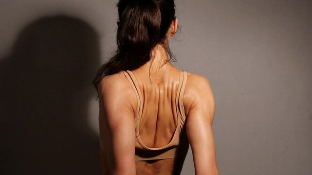 Health sport sexy woman doing stratching exercises for shoulders, scapula and healthy upper back, attractive body lifestyle. Curves female brunette  model in bra on studio low key shadow. Back view