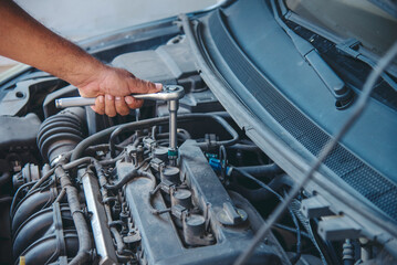 Close up Mechanic man hands repairing car auto repair shop uses jack change tyre. Man hands fixing Shock absorber machinery vehicle mechanical service. Vehicle Car overhaul maintenance engineer