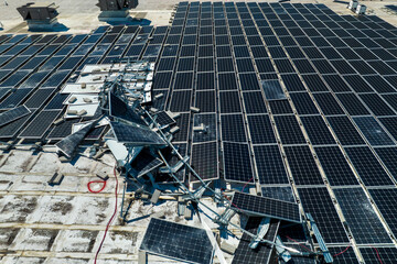 Aerial view of damaged by hurricane wind photovoltaic solar panels mounted on industrial building...
