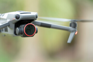 Drone aircraft with blurred fast rotating propellers and video camera flying in air