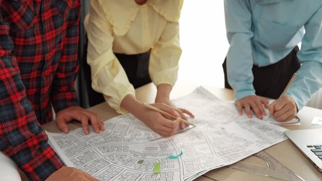 Professional engineer team discussion about house design on meeting table with architectural equipment and building blueprint scatter around at modern office. Focus on hand. Closeup. Delineation.