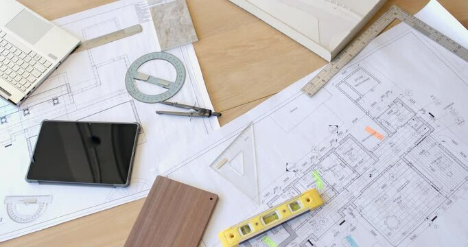 Planning construction project, architectural blueprints with tablet, compass, and level on desk