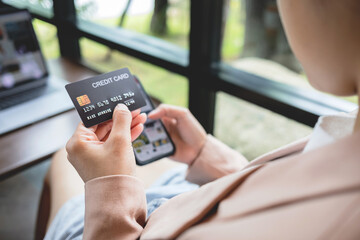 Woman hand holding credit card with smartphone for shopping and paying online using banking app.
