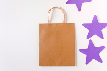An empty brown craft bag on a white background with stars. Flat lay, template and mockup for design. Brown paper shopping bag