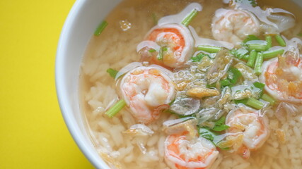 rice soup with shrimp in white bowl on yellow background