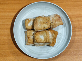 Fried tofu on a white plate. Traditional Indonesian snack.