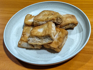 Fried tofu on a white plate. Traditional Indonesian snack.