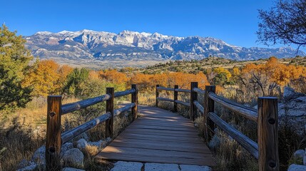 Wooden footbridge leading to majestic snowy mountain range in autumn