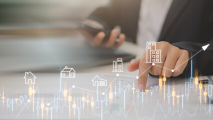 Businessmen analyze residential real estate investments using digital graphs and house icons,...
