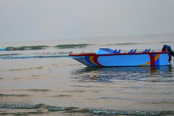 This picture is of the Mandarmani coast in the Bay of Bengal near Digha, India, where an empty fiberglass single-hull boat floats on the billow waves.