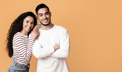 Fototapeta premium Happy Millennials. Portrait Of Smiling Romantic Middle Eastern Couple Posing Over Yellow Background, Cheerful Young Man And Woman In Casual Clothes Standing Together In Studio, Copy Space