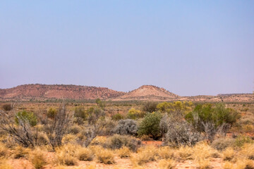 Rocky hills behind a treeless dry savannah landcape with dry grass and scrub  near Erldunda in the Norther Territory of Australia