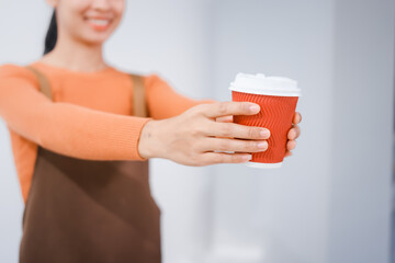 Asian female barista with a beautiful smile, skillfully making coffee in a cozy small shop, creating a warm and welcoming atmosphere for customers in the charming cafe