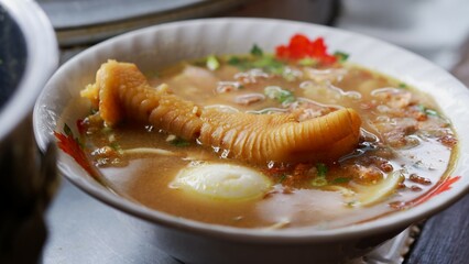 Chicken soup with shredded chicken, chicken feet, eggs, sliced cabbage, vermicelli in broth. Indonesian food.