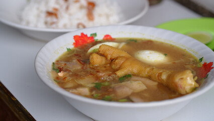 Chicken soup with shredded chicken, chicken feet, eggs, sliced cabbage, vermicelli in broth. Indonesian food.