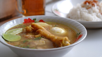 Chicken soup with shredded chicken, chicken feet, eggs, sliced cabbage, vermicelli in broth. Indonesian food.