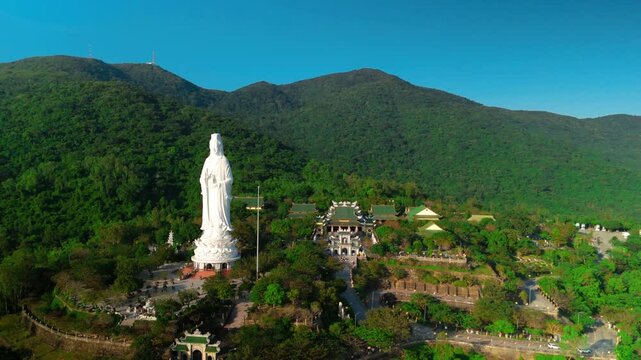 Aerial perspective revealing white lady buddha statue towering over verdant landscape near ho quoc pagoda, symbolizing spiritual tranquility on phu quoc island, vietnam