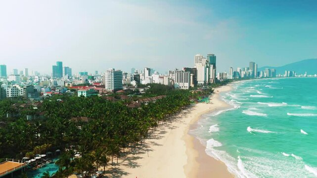 Da nang skyline rising above sandy coastline, modern buildings contrasting pristine turquoise waters of south china sea, capturing vietnamese urban natural landscape
