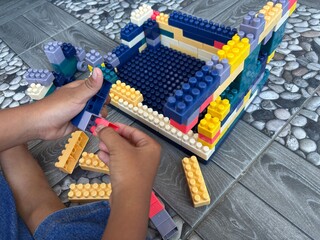 A close-up of child hands assembling colorful building blocks, creating a toy structure. Perfect for concepts of creativity, childhood development, education, and playtime activities for kids