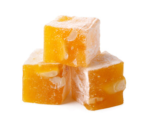 Delicious yellow candy squares with nuts stacked on a white surface