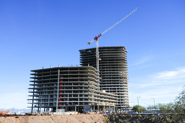 High-rise construction featuring two partially completed skyscrapers with a crane on-site under a...