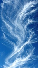 Fototapeta premium Ethereal wisps of clouds dance against a vibrant blue sky, creating a mesmerizing natural artwork that evokes tranquility and wonder.