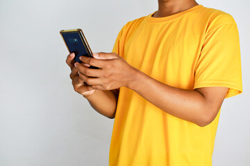 Person holding a black cellphone with a gold case wearing a yellow shirt against gray background