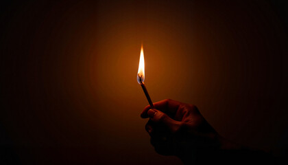 Hand holding a lit match against a dark background