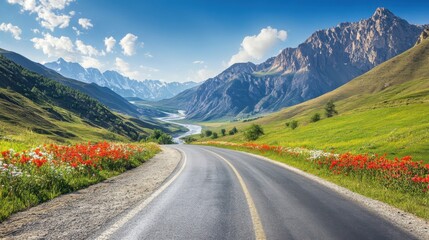Fototapeta premium Scenic road winding through a valley with a majestic mountain range in the background under a clear blue sky