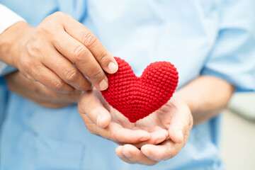 Asian elder senior woman patient holding red heart in hospital.