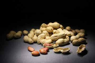 A pile of peanuts in shell on a dark background.
