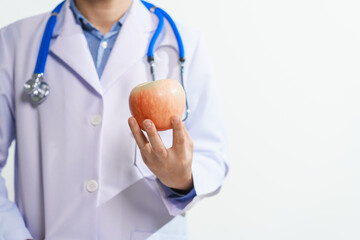 A male nutritionist holding an apple, surrounded by mixed fruit, emphasizing care for health and wellness,promoting nutritious eating, and offering guidance for a balanced, healthy lifestyle against