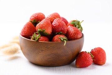 Strawberry fruit in wooden bowl on white background