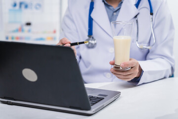 Fototapeta premium A male nutritionist working at a hospital desk, holding an apple and mixed fruit, offering care, health advice, weight loss guidance, and eating tips online for patients seeking nutrition support
