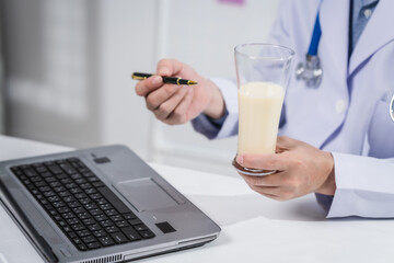 A male nutritionist working at a hospital desk, holding an apple and mixed fruit, offering care,...