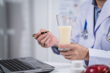 A male nutritionist working at a hospital desk, holding an apple and mixed fruit, offering care, health advice, weight loss guidance, and eating tips online for patients seeking nutrition support