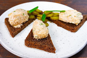Unique appetizer featuring rye bread and creamy spread with pickles Savory vegetable pie served with fresh garnishes on a white plate