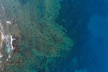 Aerial drone bird's eye view of tropical rocky seascape and beach with turquoise and sapphire clear waters