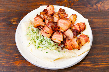 Deliciously prepared bacon wrapped meat served on a white plate Savory vegetable pie served with fresh garnishes on a white plate